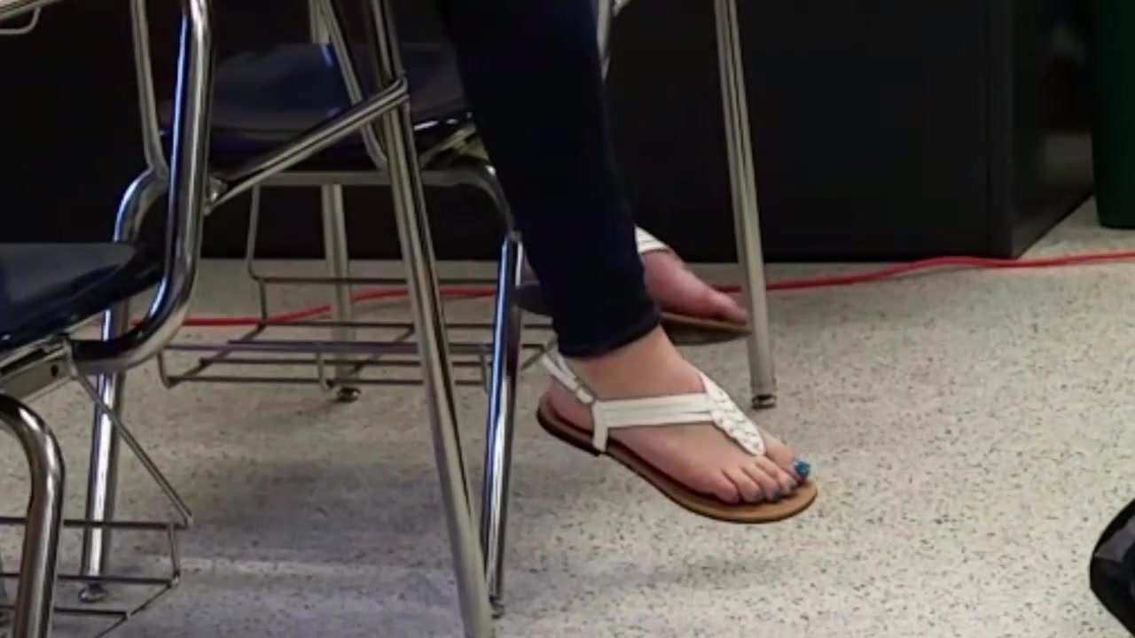 College girl with blue toes dangles her sexy feet from table